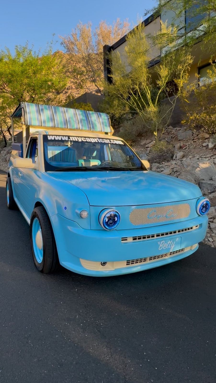 The Riviera blue Capri Car under a resort porte-cochère with palm trees