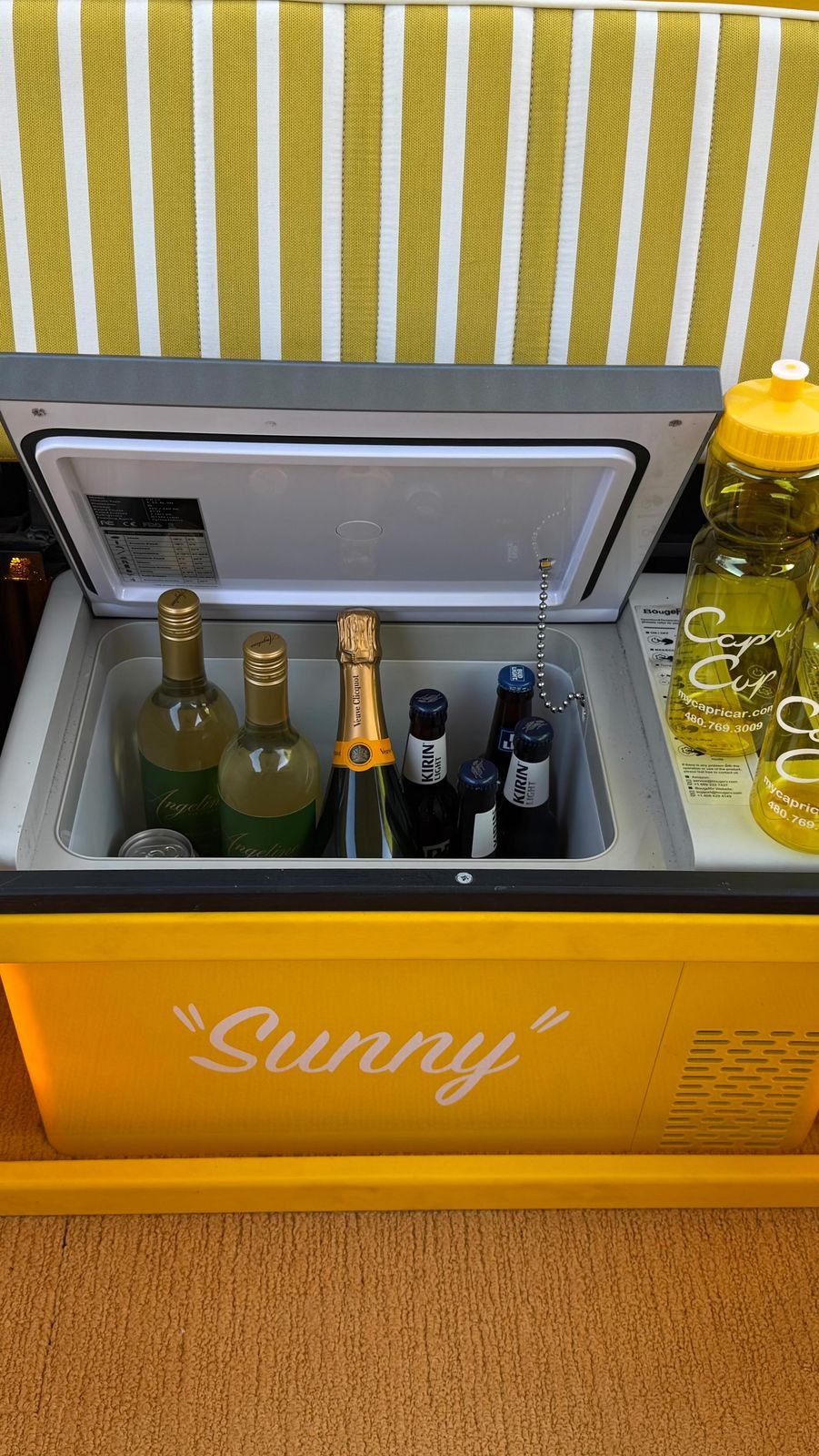 Inside Sunny: striped bench seating, a built-in fridge with chilled bottles, and speakers set into the sides